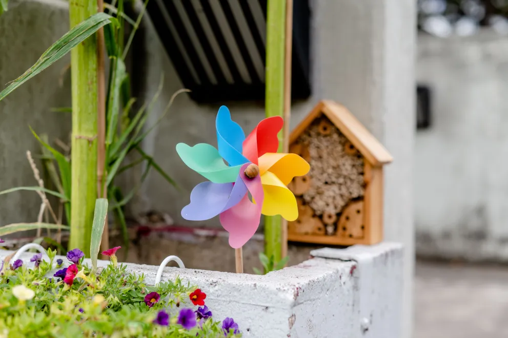 Betonblumenkasten mit bunten Blumen und Windrädchen